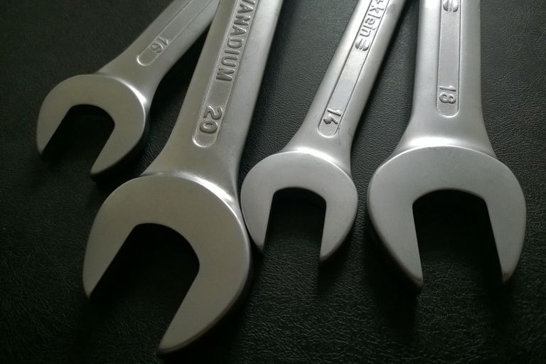 Mehrere Schraubenschlüssel nebeneinander auf dunklem Hintergrund